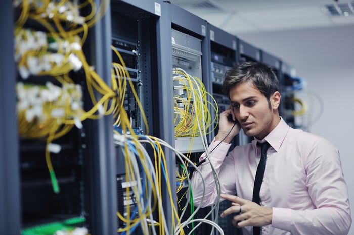 young business man computer science engeneer talking by cellphone at network datacenter server room asking for help and fast solutions and services